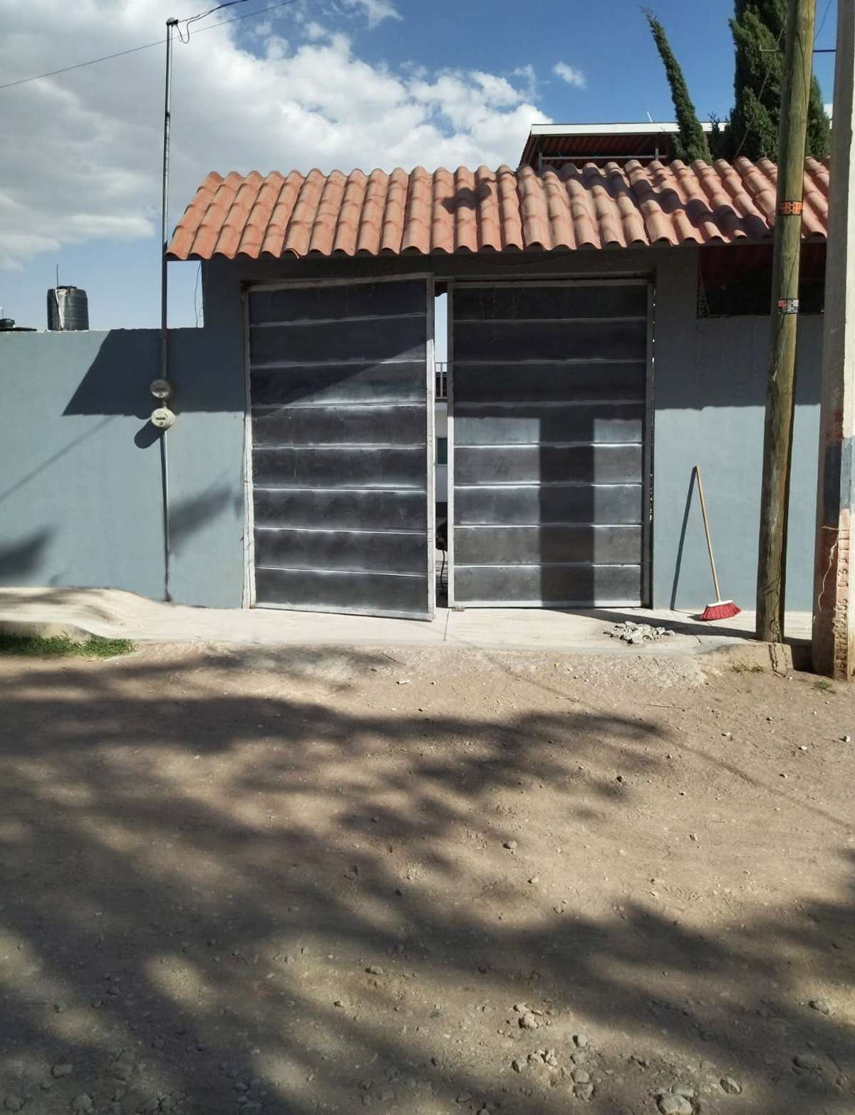Portón metálico gris en acceso residencial